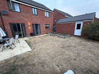 From the back right corner of the garden, looking back towards the house and gate.