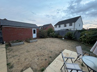 Looking from the patio across the garden towards the garage, showing the open expanse of bare ground.